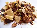 This retail mixture contains rooibos, coconut, ginger, cinnamon, apple, cardamom, black pepper and almond.