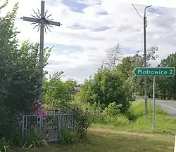Road sign with name of the village and cross