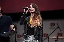 White woman with brunette hair speaking into a microphone.