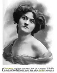 Photograph of a young white woman, in a glamourous pose, with bare shoulders and voluminous wavy hair.