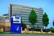 A photo of a curved glass building with a CDC sign in front of it