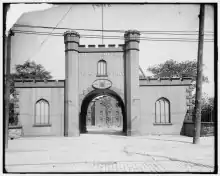 Black and white photo of a castle-like gatehouse with an arched opening