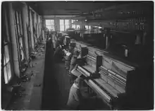 Row of key fitters at the Cable Company St. Charles Il. factory Making Wellington Pianos.
