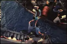Vietnamese man hands a child to waiting American crewmen, photographed from above