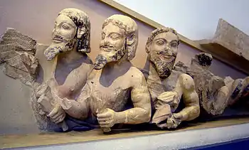 Monstruo de tres cabezas y cola enroscada que se ajusta al extremo derecho de un frontón (en el Hecatompedón o en algún otro templo destruido de la Acrópolis de Atenas).