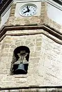 Detalle del campanario de la iglesia parroquial de Casas Altas, con detalle del reloj y una campana (2006).