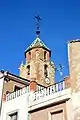 Vista parcial (suroccidental) de la torre-campanario de la iglesia parroquial de la Natividad en Tormón (Teruel), desde la Plaza (2017).