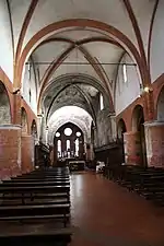 La nave de la abacial, con sus pilares de ladrillo; la bóveda del transepto decorada con frescos; al final, el fondo del ábside plano y sus tres vidrieras, tipicamente cistercienses.