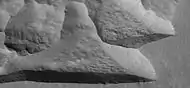 Ampliación de la depresión amurallada en recta (imagen HiRISE). La pared del sur es más oscura que la pared del norte.