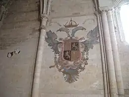 Escudo del emperador Carlos I pintado en el primer tramo recto del presbiterio.