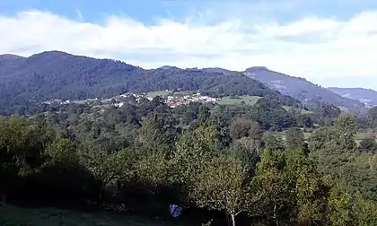 Vista de Aces con el Nalón en primer plano entre la sombra de los árboles en una hermosa mañana otoñal