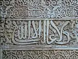 El lema nazarí ("No hay conquistador sino Dios") en caligrafía árabe cursiva, inscrito en el Salón de Embajadores de la Alhambra de Granada (siglo XIV)
