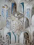 Primer plano de detalles tallados y pintados en los nichos constituyentes de una cúpula de mocárabe en la Sala de los Reyes de la Alhambra