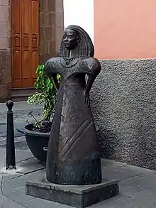 Escultura idealizada de  Arminda Masequera, realizada por Diego Higueras en 2007 y situada frente al Museo y Parque Arqueológico Cueva Pintada, Gáldar