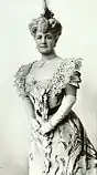 three-quarters length image of a woman in a dress with a headpiece and elbow length white gloves
