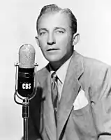 Una foto de época de Bing Crosby con traje y cantando ante un micrófono de la CBS.