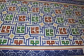 Detalle de la pared del iwán donde se encuentra el mihrab. En verde y rojo, el nombre de Mahoma se repite en letras de estilo cúfico cuadrado.