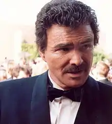 A middle-aged man, wearing a suit with a black bow tie.
