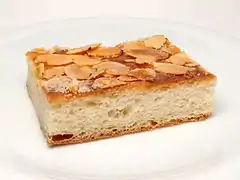 Un trozo de pastel de mantequilla adornado con almendra fileteada.