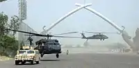 Dos helicópteros UH-60 Black Hawk tomando tierra frente a los sables del arco de la victoria en la Zona Internacional de Bagdad el 4 de julio de 2006.