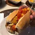 Hot-dog brasileño con tomate, maíz, batata-palha (papas paja) y cebolla.