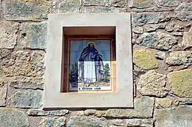 Hornacina con plafón cerámico representando a san Antón en la fachada septentrional de la torre campanario de la parroquial de Casas Bajas, 2018.