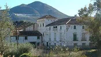 En primer plano, un cortijo, al fondo, ladera cubierta de olivares y el núcleo de población de Solera (Jaén).