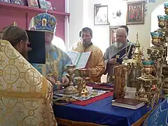 Tras la transmutación de los dones sagrados, el obispo presenta al nuevo sacerdote una porción del "Cordero" (el "Cuerpo de Cristo").
