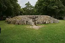 Uno de los tres cairns de Balnuaran de Clava. Existen varios subtipos: con corredor, en anillo cerrado, etc. El de la foto posee un corredor delimitado por ortostatos. Se observa el bordillo exterior de grandes rocas.