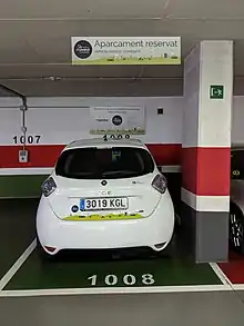 Coche eléctrico aparcado en una plaza de garaje. Se ve la matrícula y la parte trasera del coche.