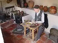 Tras el aldeano, un amplio vasar con orzas, cántaros y ollas de barro en el "Museo del Ayer" de Cogeces del Monte (Valladolid).