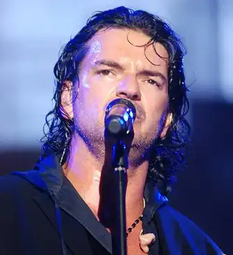 Ricardo Arjona, cantando en un micrófono.