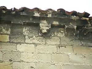 Detalle de un canecillo del tejado de la iglesia de San Juan donde se observa una cabeza animal.
