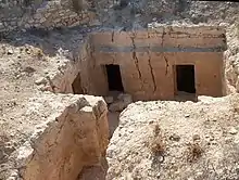 Vue plongeante sur une cavité dans le sol ouvrant sur des salles abritant des tombes puniques.