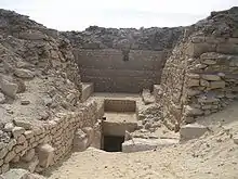 A Descending passage leads into the ground, in the midst of ruined walls.