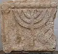Dintel de piedra tallada con la Menorá, de la Sinagoga de Estemoa, siglo III o IV.