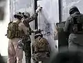 Los marines de EE. UU. Colocan una carga explosiva contra una puerta, colocada para separar la puerta de sus bisagras