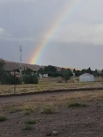 Imagen del terreno del ferrocarril en Comallo con arco iris de fondo