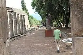 Vista de la columnata este desde el acceso norte. A la derecha se aprecia parte del murete que separaba el área sagrada y la zona de competiciones deportivas.