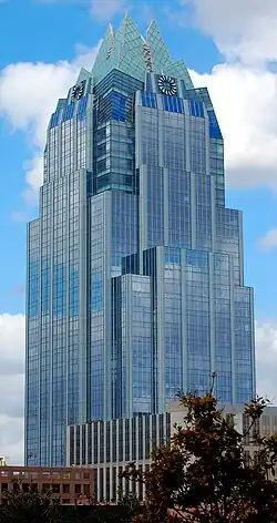 Ground view of the Frost Bank Tower; the tower has the appearance of an owl; the building has multiple setbacks; there is a cyan colored crown on the top of the building.