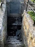 Fuente antigua de piedra con una perforación y una escalinata