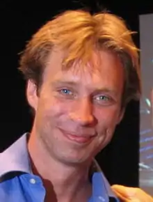 Color photograph of a middle-aged, blond-haired man posing for the camera.