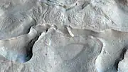 Características de flujo de tipo glacial cerca de Mamers Valles. Las escarpas y las colinas parecen retorcidas como melcocha, probablemente como resultado del lento movimiento del hielo subterráneo. Tenga en cuenta el suelo estampado en la parte superior central. Estas texturas a pequeña escala pueden ser el resultado de la sublimación (evaporación) del hielo bajo la superficie combinada con los cambios similares a melcocha en la superficie del suelo. El ancho de la imagen es de aproximadamente un kilómetro.