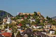 Une ville surplombée par une colline sur laquelle se trouve une forteresse médiévale.