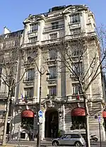 A six storey building at the corner of a terrace lined in front by bare trees