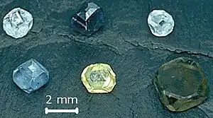 Seis cristales de diamante no faceteados, de 2-3 mm de tamaño; los colores de los diamantes son amarillo, verde-amarillo, verde-azul, azul claro, azul claro, y azul oscuro