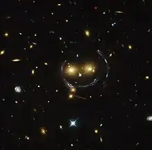 Cúmulo de galaxia - imagen de “smiley” (SDSS J1038+4849) y lente gravitatoria (un anillo de Einstein). Capturada por el telescopio espacial Hubble (HST por sus siglas en inglés).