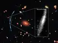Al enfocar a un cúmulo de galaxias se ha enfocado de forma gravitatoria a una galaxia en segundo plano la cual es intervenida por el cúmulo.