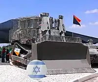 Buldózer blindado FDI D9R , con adiciones de blindaje en planchas (en adición a la protección balística y la cobertura de sus ventanas con vidrios anti-proyectiles), presentado en el comando de las fuerzas terrestres de de las FDI en la conmemoración del 60.º Día de la independencia de Israel.