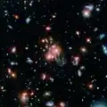Imagen del cúmulo de galaxias SpARCS1049 que capturó el Spiter y el telescopio espacial Hubble.